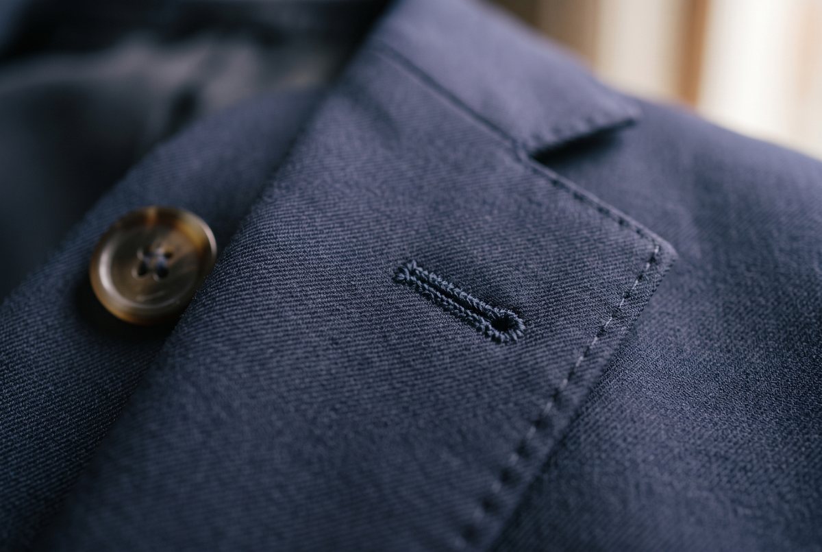 Hand sewn buttonhole on the lapel of a navy wool jacket.